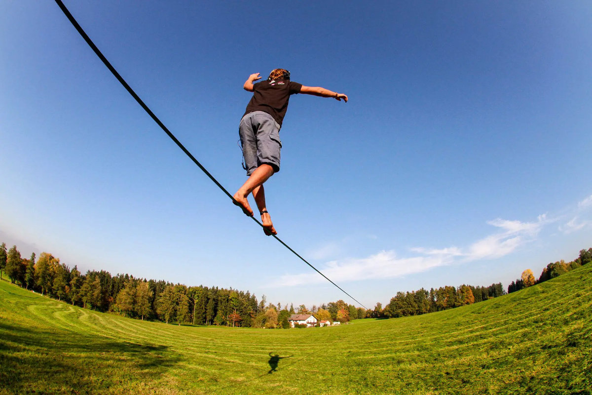 young man walking on slack line looking for balance